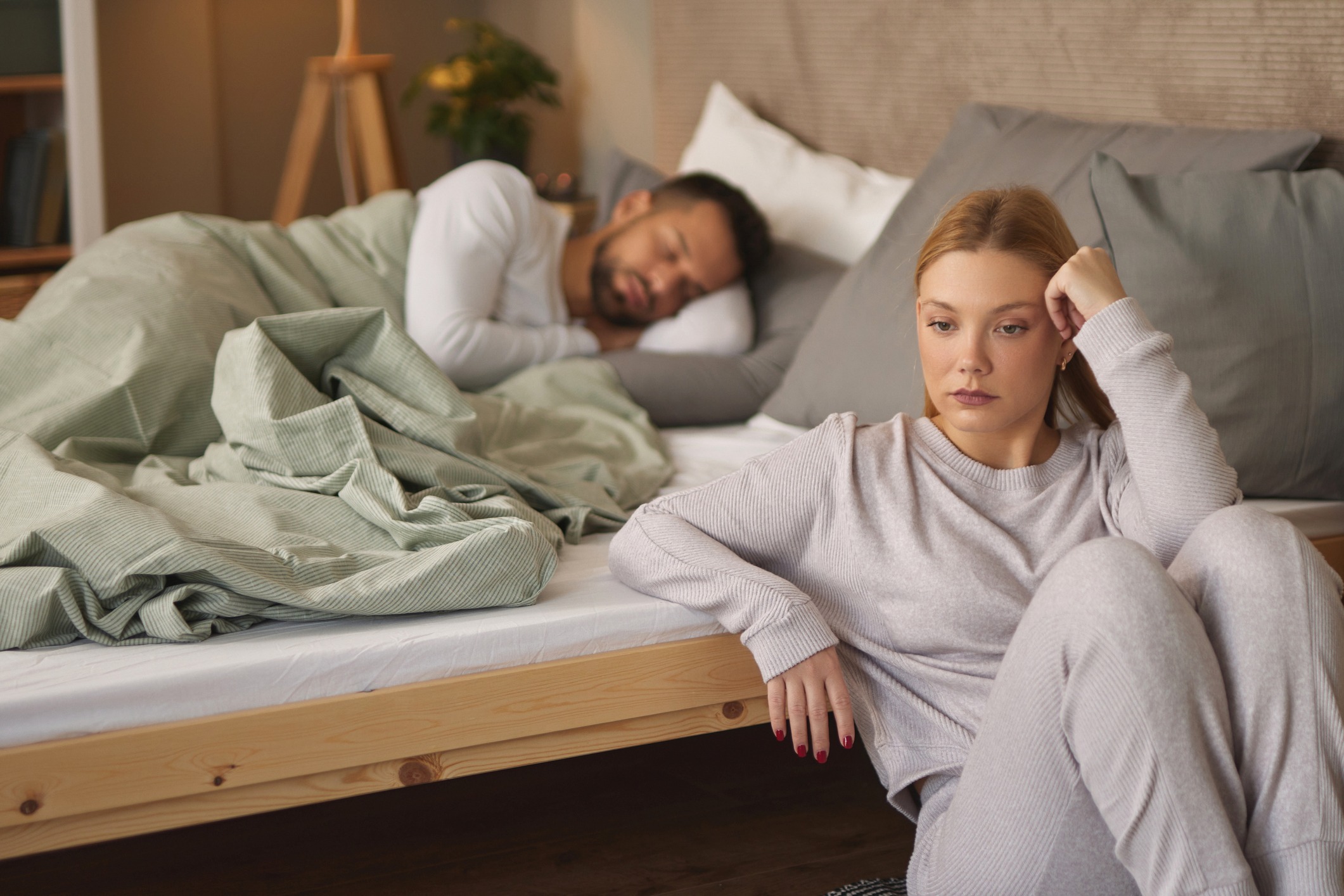 Frau wirkt nachdenklich am Bettrand, Symbolbild für sexuelle Angststörungen in der Partnerschaft.