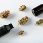 Verschiedene Darreichungsformen von medizinischem Cannabis: Blüten, Ölflasche und Vaporizer auf weißem Hintergrund.